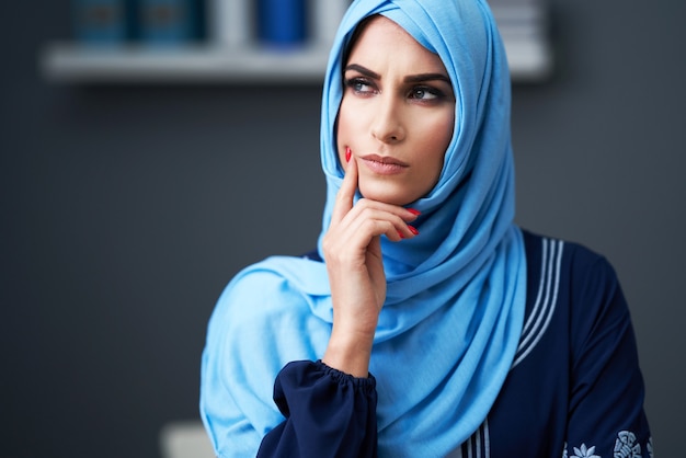 Unhappy muslim female student learning in library