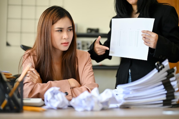 不幸で過労のアジア人女性従業員が上司から仕事の苦情を受けている