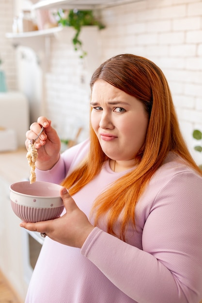 Unhappy plump woman not liking her food while being on a strict diet
