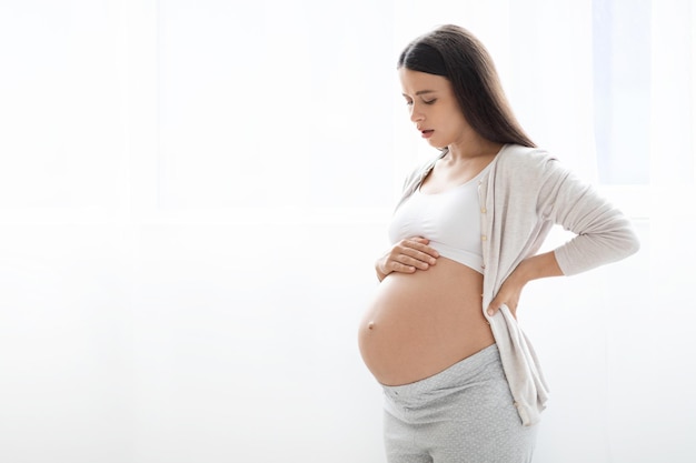 Unhappy pregnant woman having back pain copy space