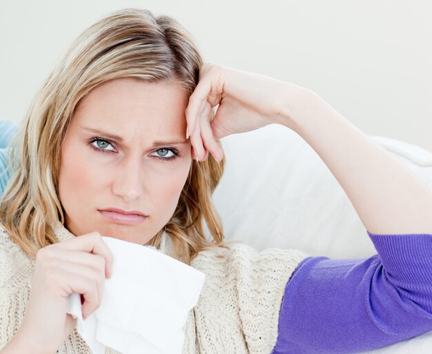 Unhappy sick woman holding tissues looking at the camera 