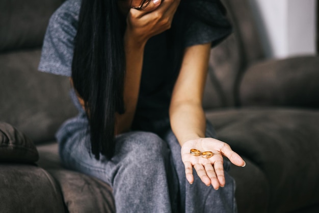 Unhappy woman holding wedding ring suffering from relations breakup or getting divorced