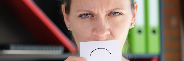 写真 オフィスで不幸な女性は彼女の口の事業の失敗の前に悲しい感情で紙を保持し、