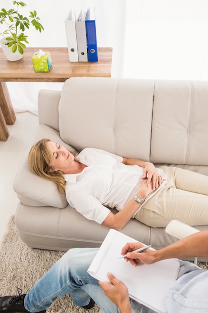 Unhappy woman lying on couch and talking to therapist 