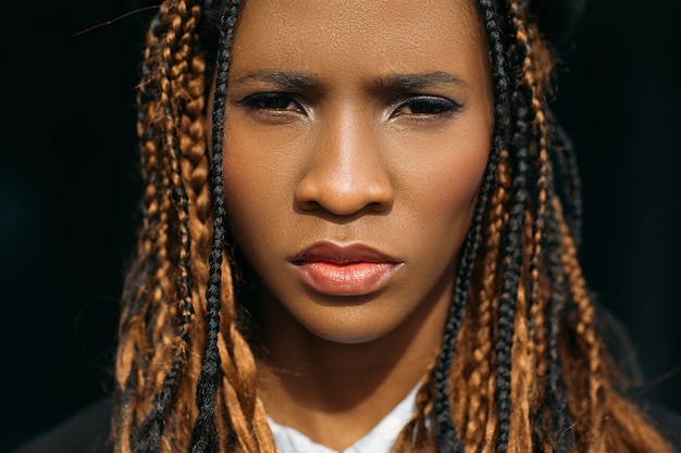 Unhappy woman portrait. Sad black female. Grumpy young girl on dark background, unimpressed facial expression, melancholy concept