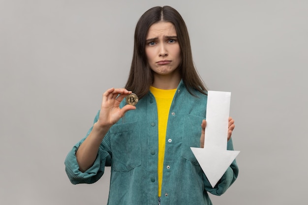 Unhappy woman showing downgrade of bitcoin expressing sad upset\
emotions looking at camera