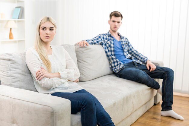 Несчастная женщина сидит рядом с мужчиной на диване