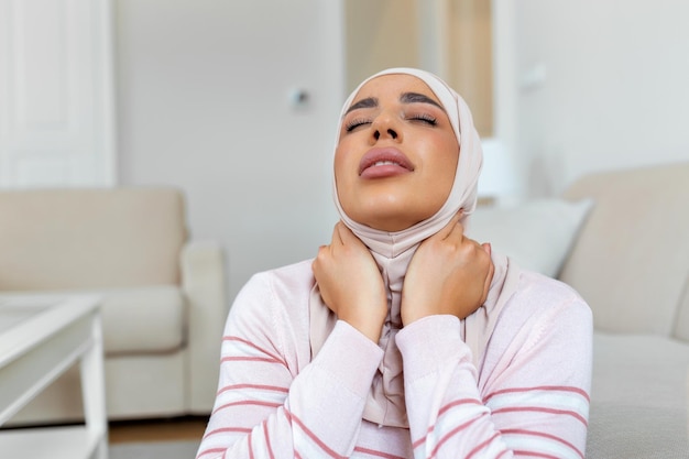 Unhappy young Arabic muslim woman with hijab suffering from pain in the neck