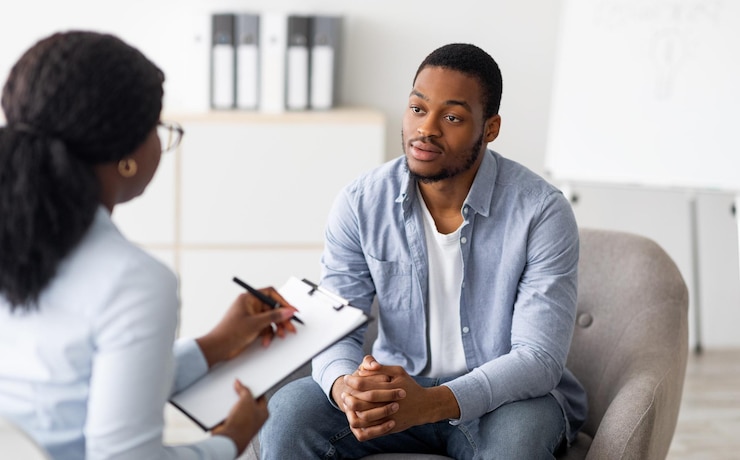 Photo unhappy young black man having session with professional psychologist at mental health clinic