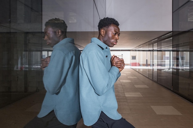 Unhappy young black man standing in passage near glass wall