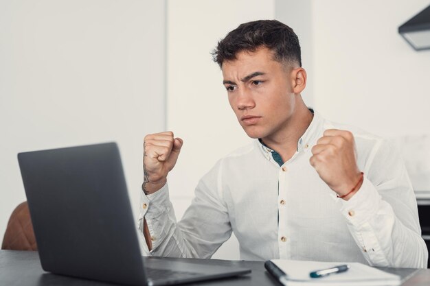 Unhappy young caucasian male worker in glasses look at laptop