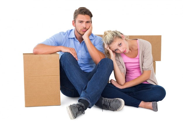 Unhappy young couple sitting beside moving boxes
