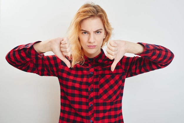 Photo unhappy young girl holding a thumbs down