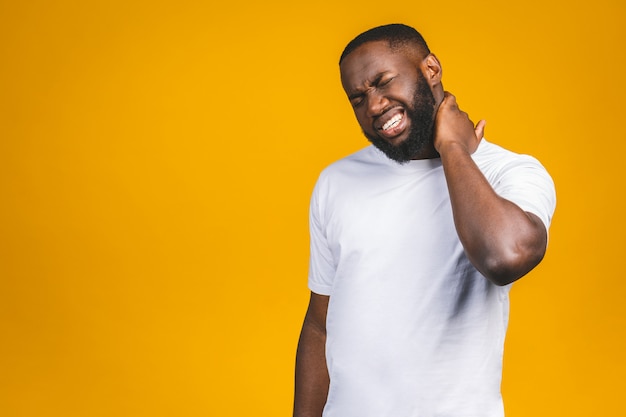 Unhappy young handsome african american man with really bad neck pain, after long hours of work, studying, isolated white wall. negative human emotions, facial expressions