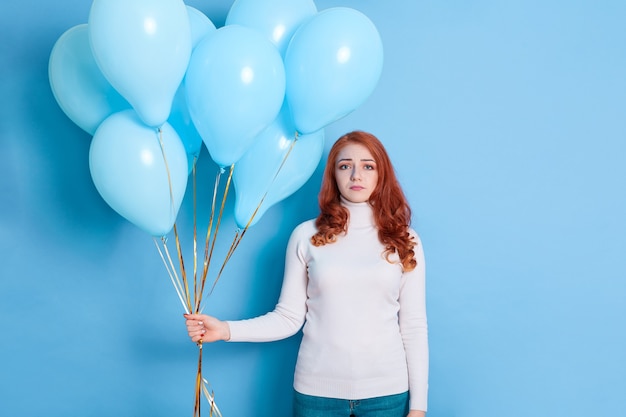 Unhappy young woman with balloons