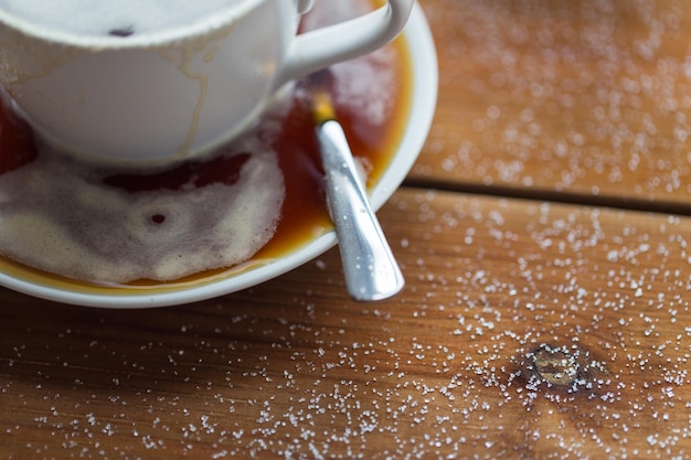 unhealthy eating, object and drinks concept - close up coffee cup and sugar poured on wooden table