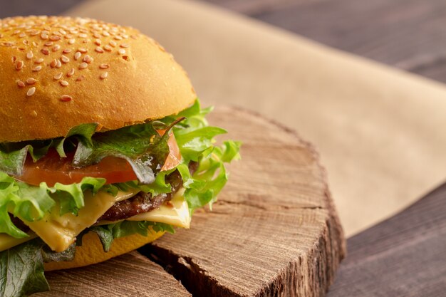 Unhealthy fatty burger with meat, cheddar cheese, lettuce. Fast appetizing street burger