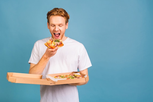 unhealthy food! happy hungry redhead young student man eating pizza 