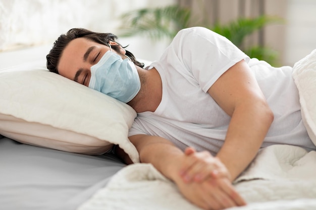 Uomo malsano con maschera facciale che soffre di virus a letto