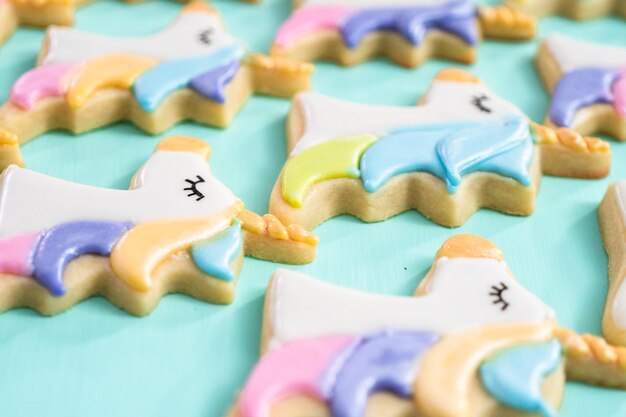 Photo unicorn sugar cookies decorated with royal icing and food glitter on a blue background.