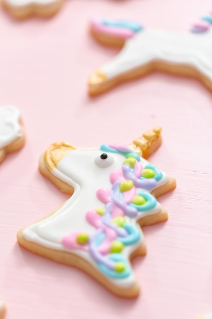 Unicorn suiker koekjes versierd met royal icing op roze achtergrond.
