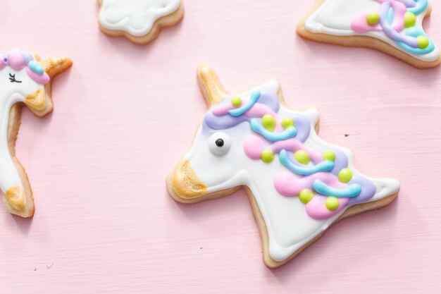 Unicorn suiker koekjes versierd met royal icing op roze achtergrond.
