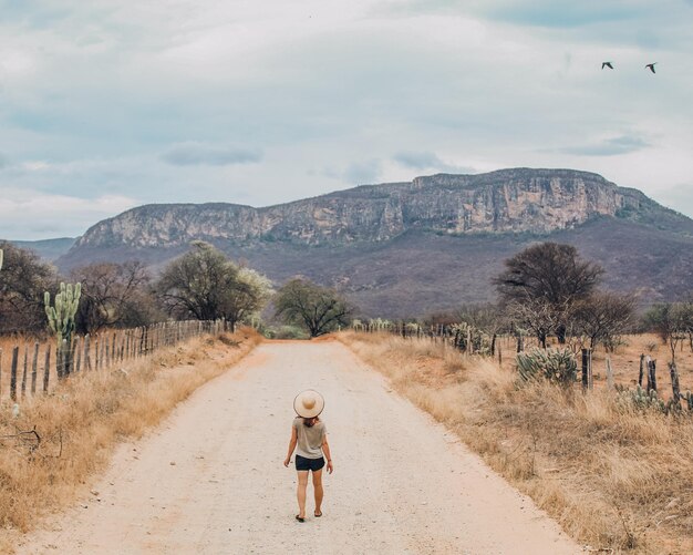 Photo unidentified tourist walking along a rural road with serra de bom sucesso in the background bahia