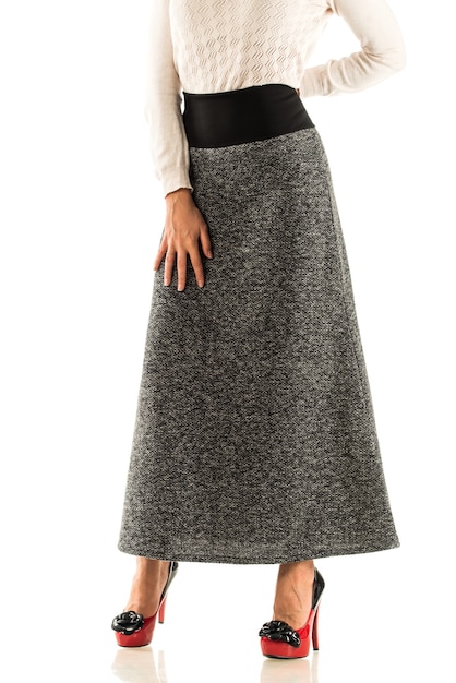 Unidentified young woman in a short white sweater and a long skirt and high heels posing  Concept of stylish women's clothing.