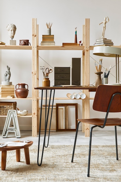 Uniek interieur van een kunstenaarswerkruimte met stijlvol bureau, houten ezel, boekenkast, kunstwerken, schilderaccessoires, decoratie en elegante persoonlijke spullen. Moderne werkkamer voor kunstenaar..