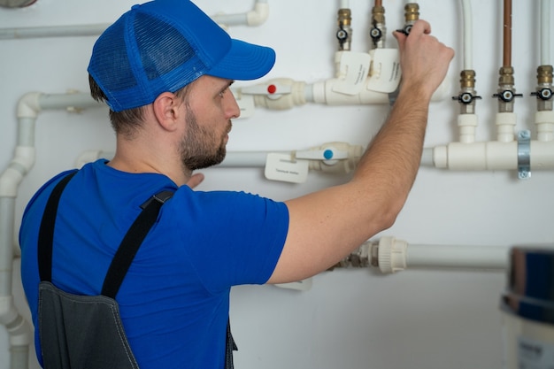 Uniformed plumber is at work  closing and opening the taps