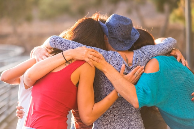 Фото Объединитесь вместе, как команда и группа друзей-женщин. 7 красивых женщин обнимаются все вместе под солнечным светом и закатом ради дружбы, отношений и успеха. вечные друзья.