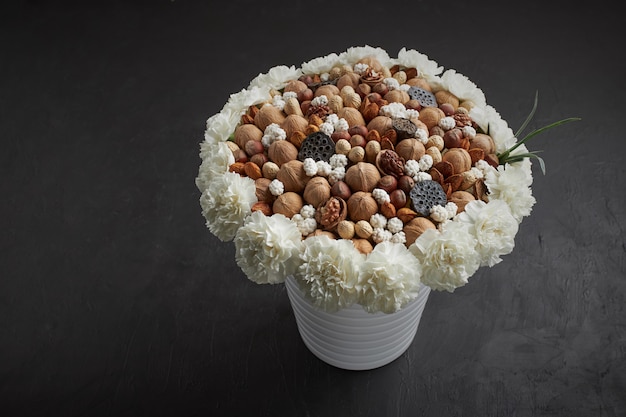 Unique bouquet made up of different types of nuts, decorated with flowers