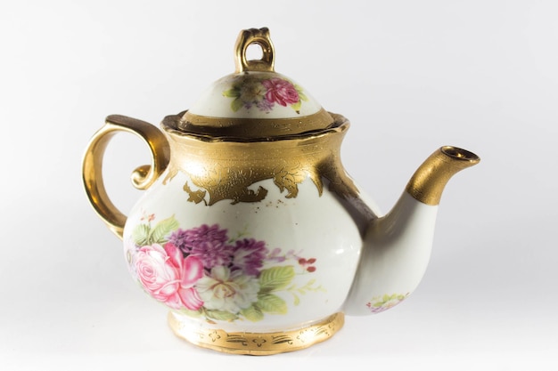 Уникальный чайник и стакан с золотыми украшениями и белым фоном