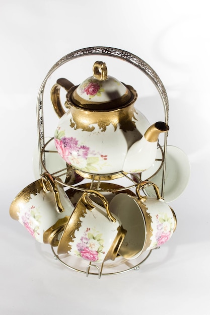 Уникальный чайник и стакан с золотыми украшениями и белым фоном