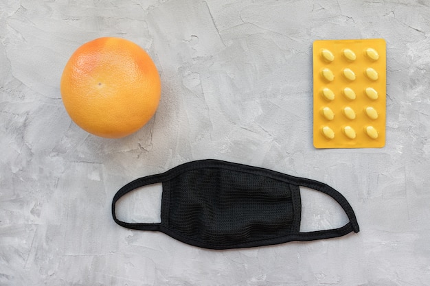 Unisex reusable black cotton mouth masks with grapefruit and pills in blister pack