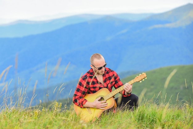 Foto all'unisono con la natura escursionista musicista trova ispirazione in montagna mantieni la calma e suona la chitarra uomo con la chitarra in cima alla montagna musica acustica musica per l'anima suonare musica suono di libertà