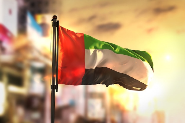 Photo united arab emirates flag against city blurred background at sunrise backlight