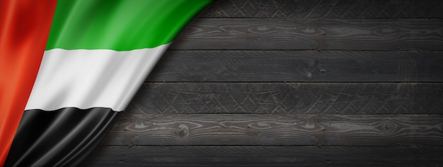 United Arab Emirates flag on black wood wall. panoramic.