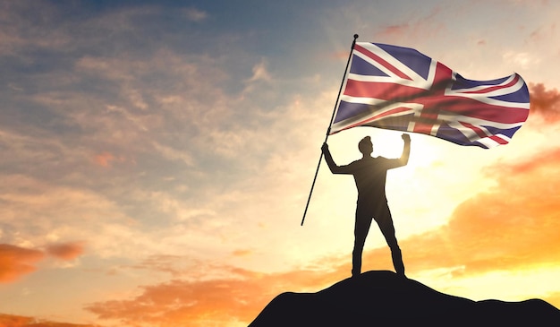 United Kingdom flag being waved by a man celebrating success at the top of a mountain 3D Rendering