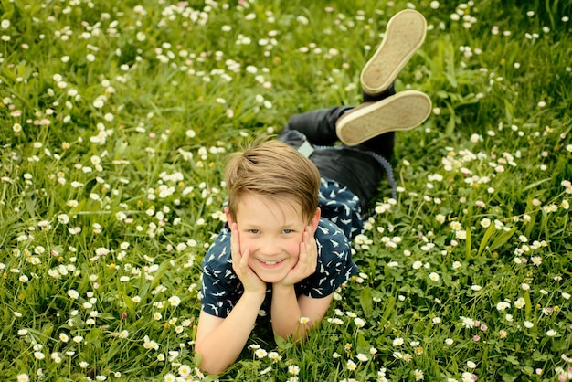 フィールドとドリーミンで楽しんでいる草の背景に横たわっている自然概念の子供との団結かわいい子供男の子