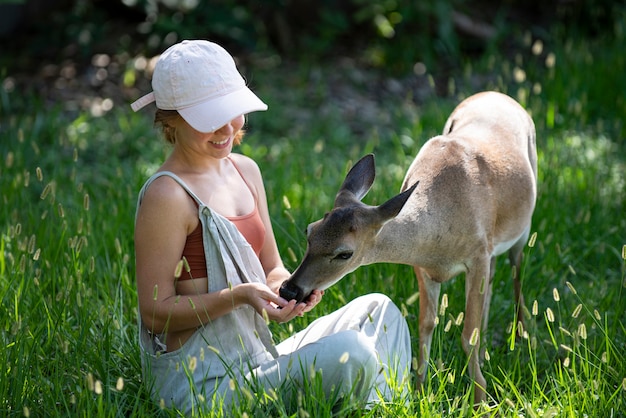 L'unità con la natura ragazza nutre i cervi bambi animali selvatici concetto donna che alimenta l'animale fulvo al park