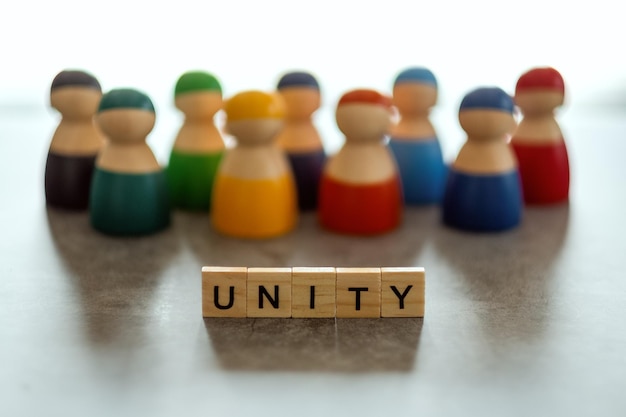 Фото Слово единства на деревянных блоках с группой людей на заднем плане