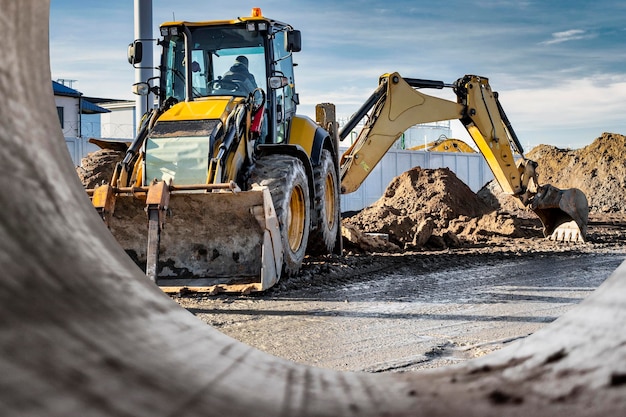 A universal excavator or loader is working on a construction site against a cloudy sky Earthworks at a construction site Modern earthmoving equipment The contractor is doing construction work