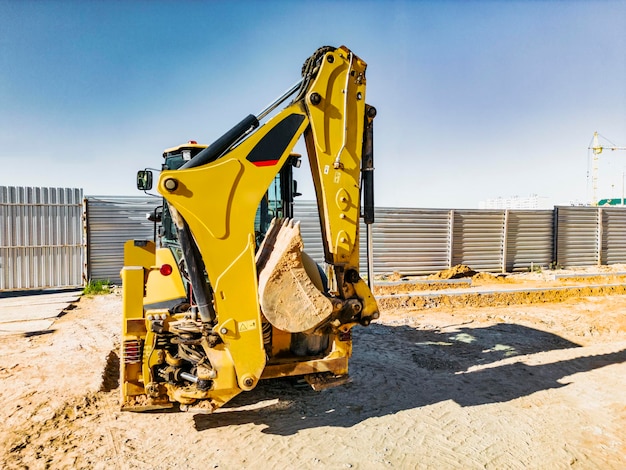 Universal excavator or loader with folded bucket at construction site Universal construction equipment Rental of construction equipment Contract for construction work