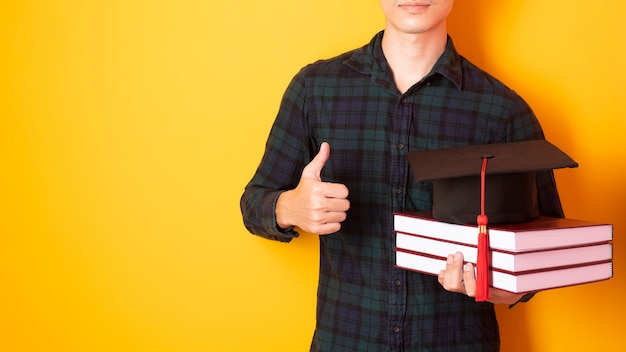 Universitaire man is blij met afstuderen op gele achtergrond