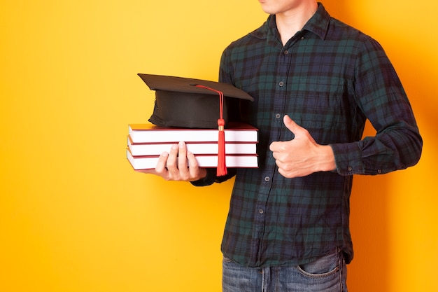 Universitaire man is blij met afstuderen op gele achtergrond
