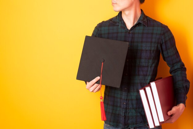 Universitaire man is blij met afstuderen op gele achtergrond