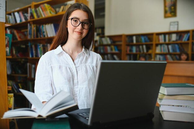 Universiteitsbibliotheek, mooi, slim, kaukasisch, meisje, gebruik, laptop, schrijft, aantekeningen, voor, papier, essay, studeren, voor, klassikaal, opdracht, gerichte, studenten, leren, studeren, voor, universiteit, examens, zijaanzicht, verticaal