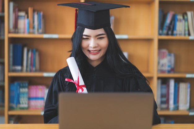 University graduate in graduation gown and mortarboard celebrates in a virtual graduation ceremony