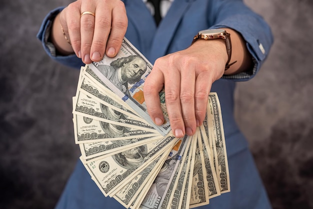 Преподаватель университета в костюме берет взятки в долларах и прячет деньги в кармане Концепция крупных взяток в учебных заведениях